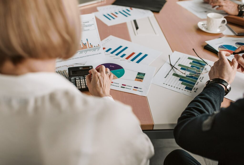 People sitting at the table with charts laying on it.