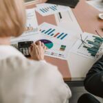 People sitting at the table with charts laying on it.