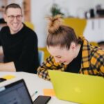 Man and woman sitting at the desk and laughing.